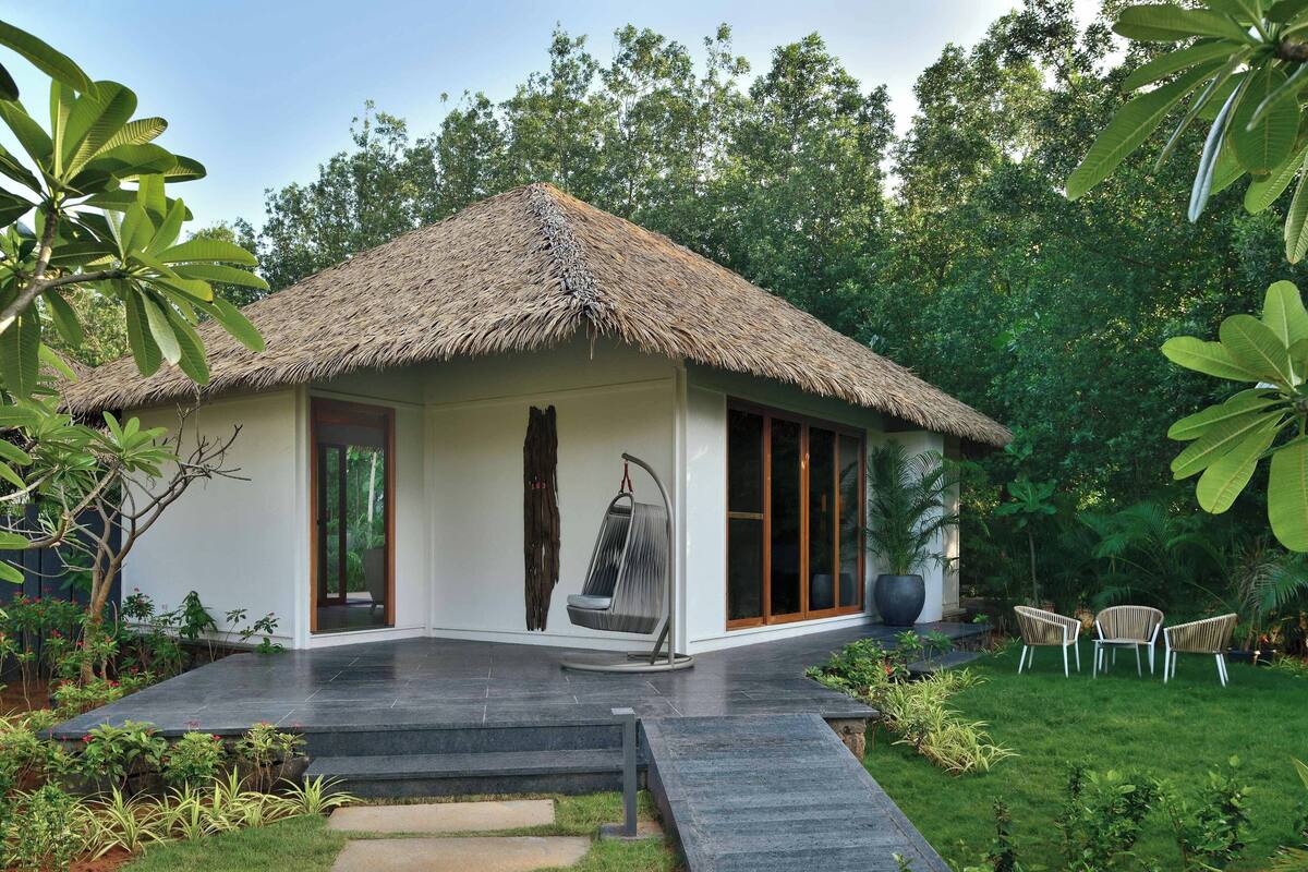 A modern house with a thatched roof, a glass door, and a swing chair.
