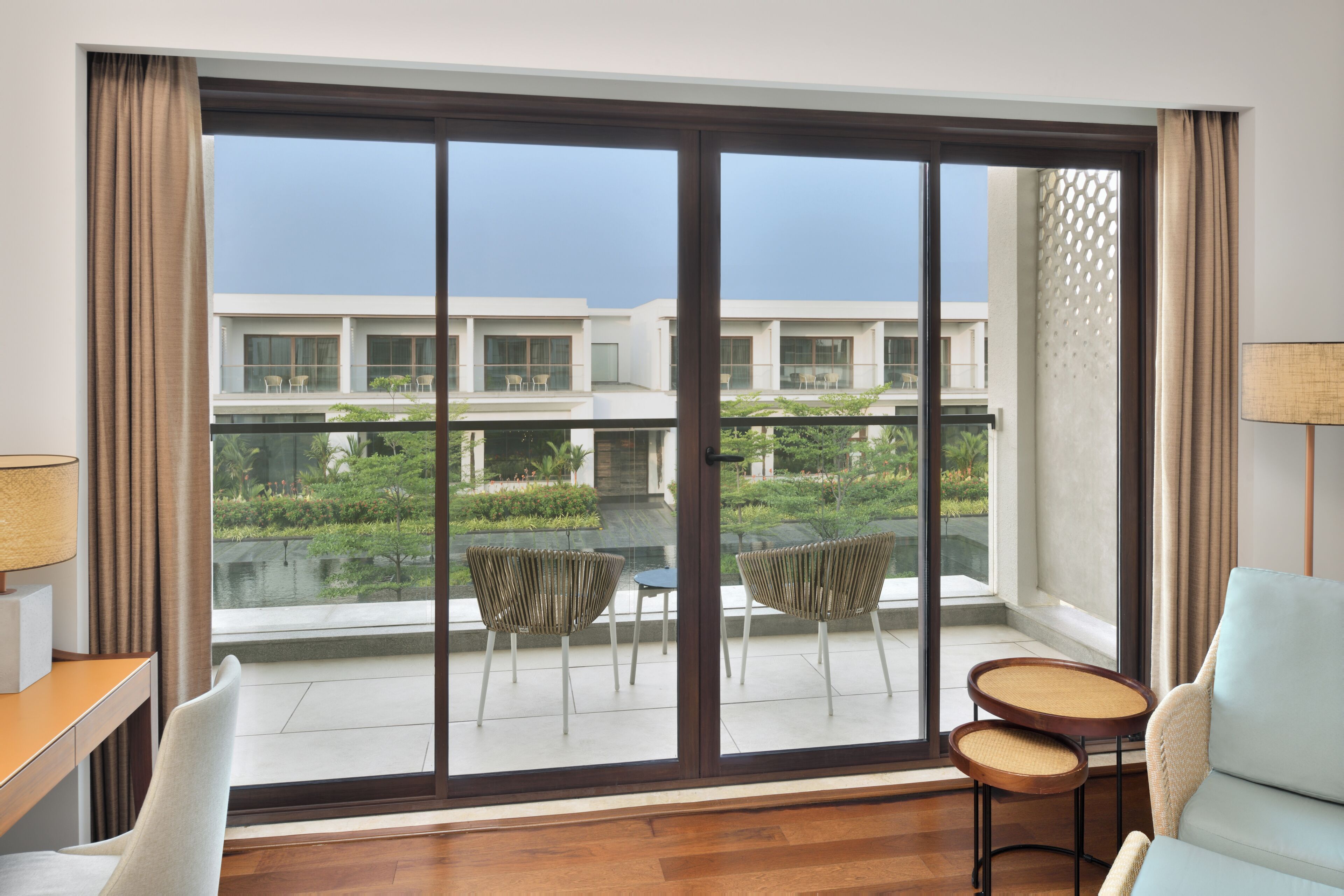 A room with a large sliding glass door, a sofa, a small round table, and a lamp.
