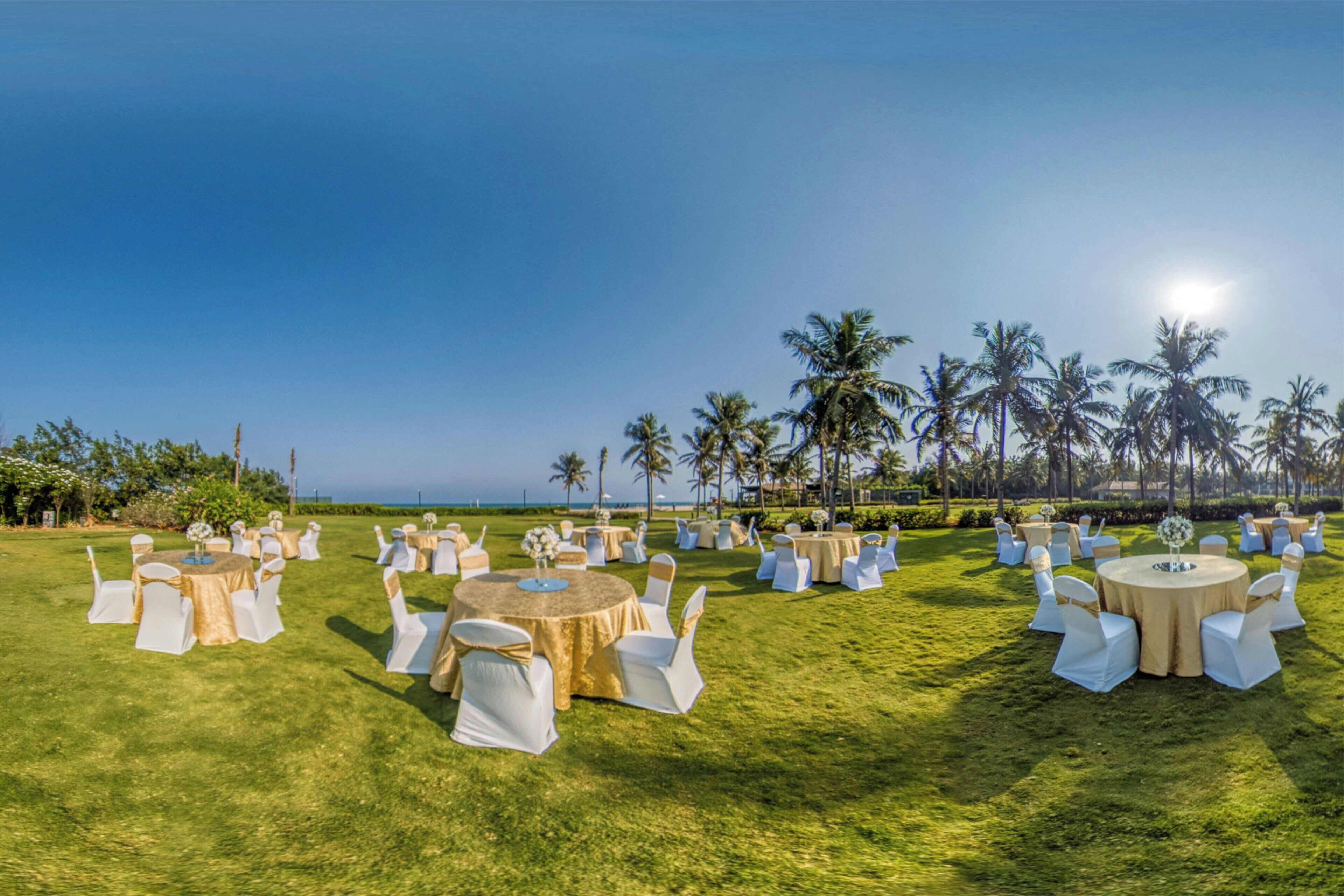 A well-maintained outdoor venue with multiple round tables and white chairs, set up for an event.