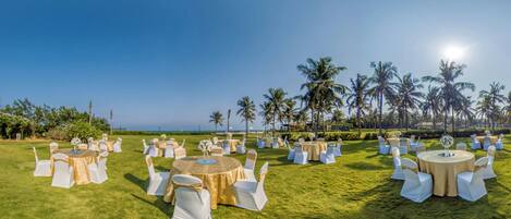 A well-maintained outdoor venue with multiple round tables and white chairs, set up for an event.