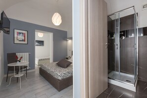 Un dormitorio moderno con cama, mesita de noche y una pequeña zona de estar.