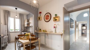 A modern kitchen with a dining area, wooden cabinets, a built-in oven, and a wall clock. - San Peter Angels Two (Rome)