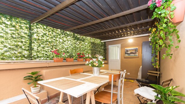 An outdoor patio with a table and chairs, surrounded by potted plants and a green wall. - San Peter Angels Two (Rome)