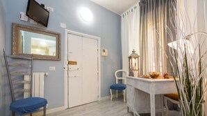 A room with a white door, a mirror, a table with a lamp, and a chair. - San Peter Angels Two (Rome)