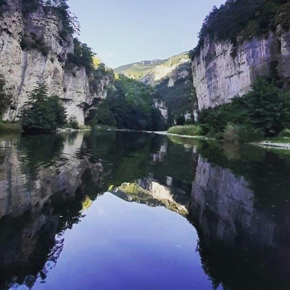 A calm river reflecting the surrounding cliffs and greenery.