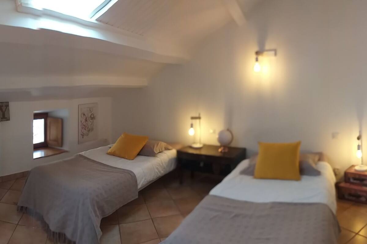 A bedroom with two beds, a skylight, a radiator, and a wall with a 'FAMILY' sign.