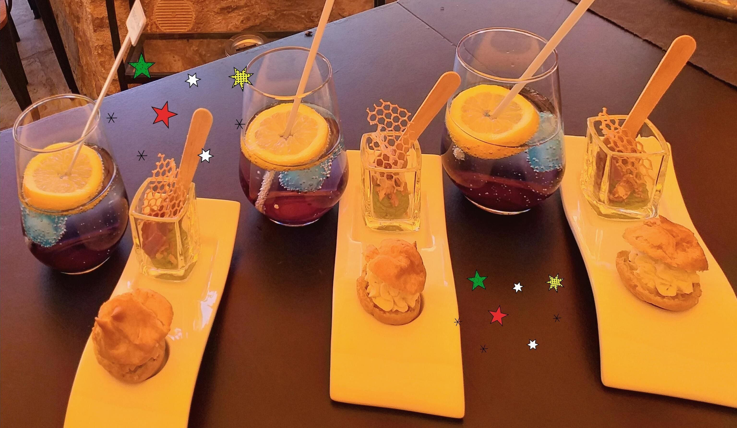 A table with six glasses of beverages, each with a slice of orange and a biscuit.