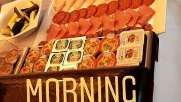 Un bufé con diversas opciones de comida, incluyendo frutas, carnes y pasteles.