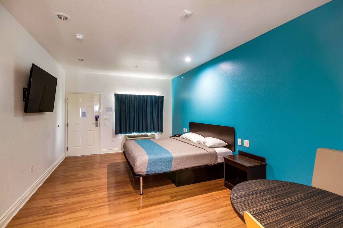 A bedroom with a bed, bedside table, and a TV mounted on the wall.