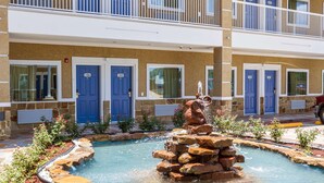 A hotel with a pool area featuring a rock fountain and a stone pathway. - Motel 6 Houston, TX - North (Houston)