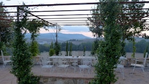 An outdoor patio with a stone wall, metal chairs, and a table.