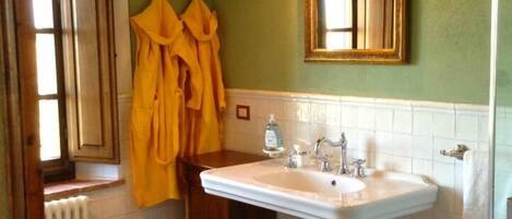 Un baño con lavamanos blanco, espejo y alfombra de baño amarilla.