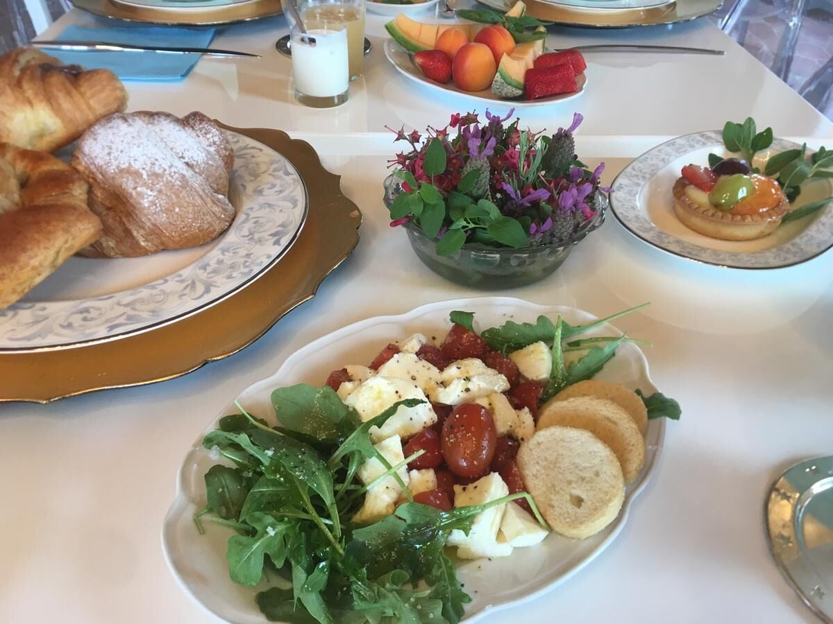 Un tavolo con diversi prodotti per la colazione, tra cui pasticcini, un'insalata di frutta, un'insalata con formaggio e un dessert.