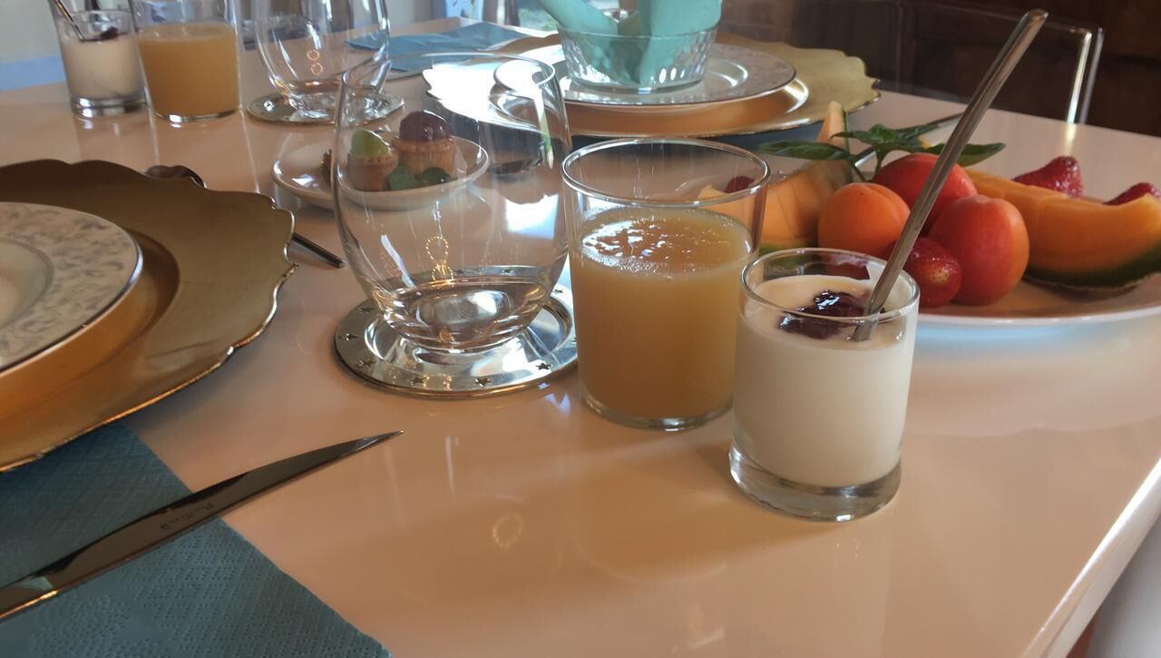 Una mesa de desayuno con diferentes platos, incluyendo fruta y un vaso de jugo.