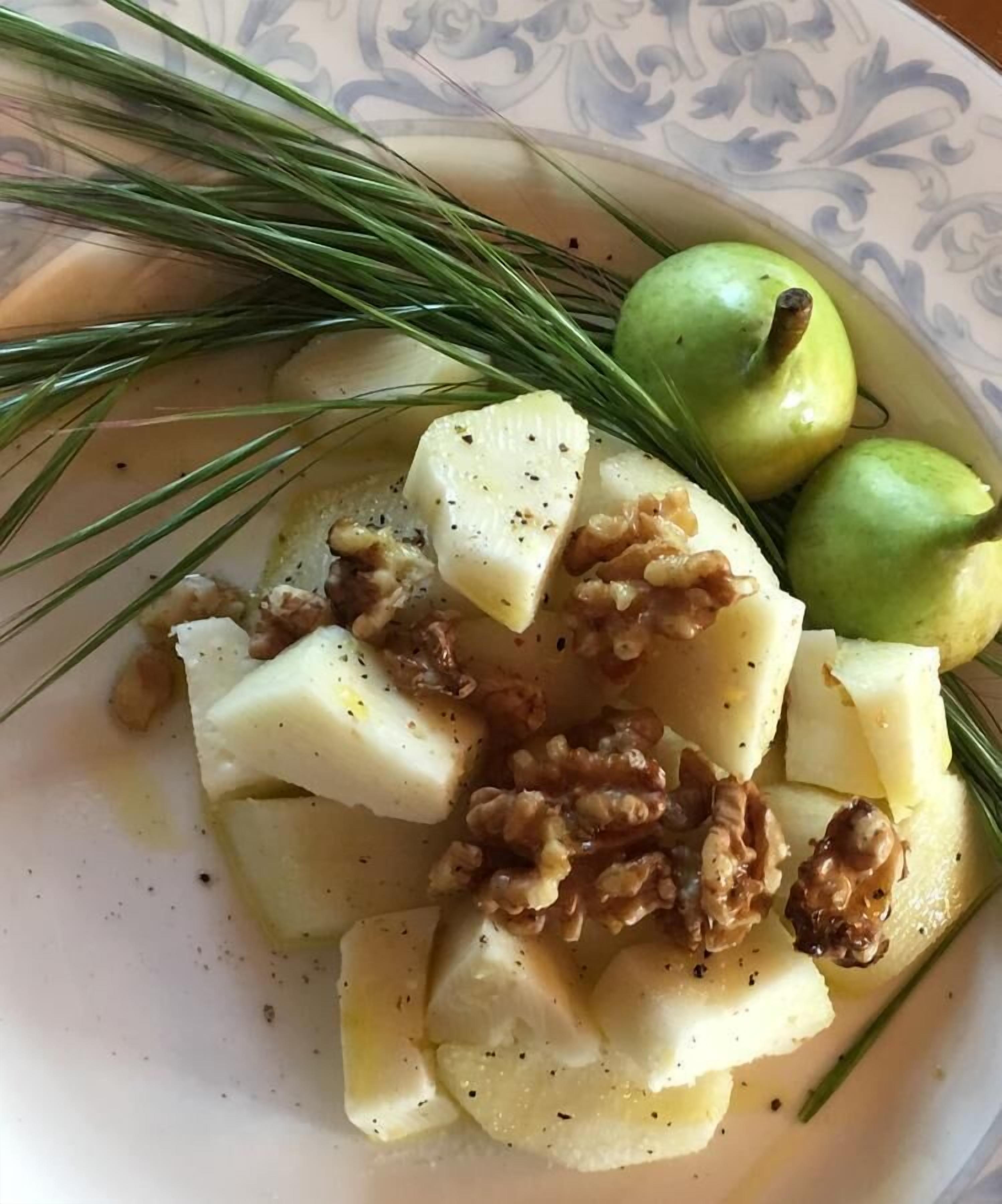 Une assiette contenant des pommes de terre coupées en dés, des noix et des pommes vertes.