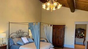 A four-poster bed with a canopy, a wooden wardrobe, and a chandelier.