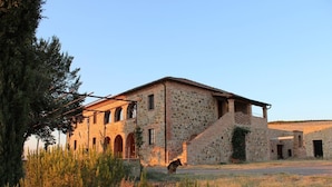 A stone building with a central courtyard, arched doorways, and a staircase leading to an upper level.