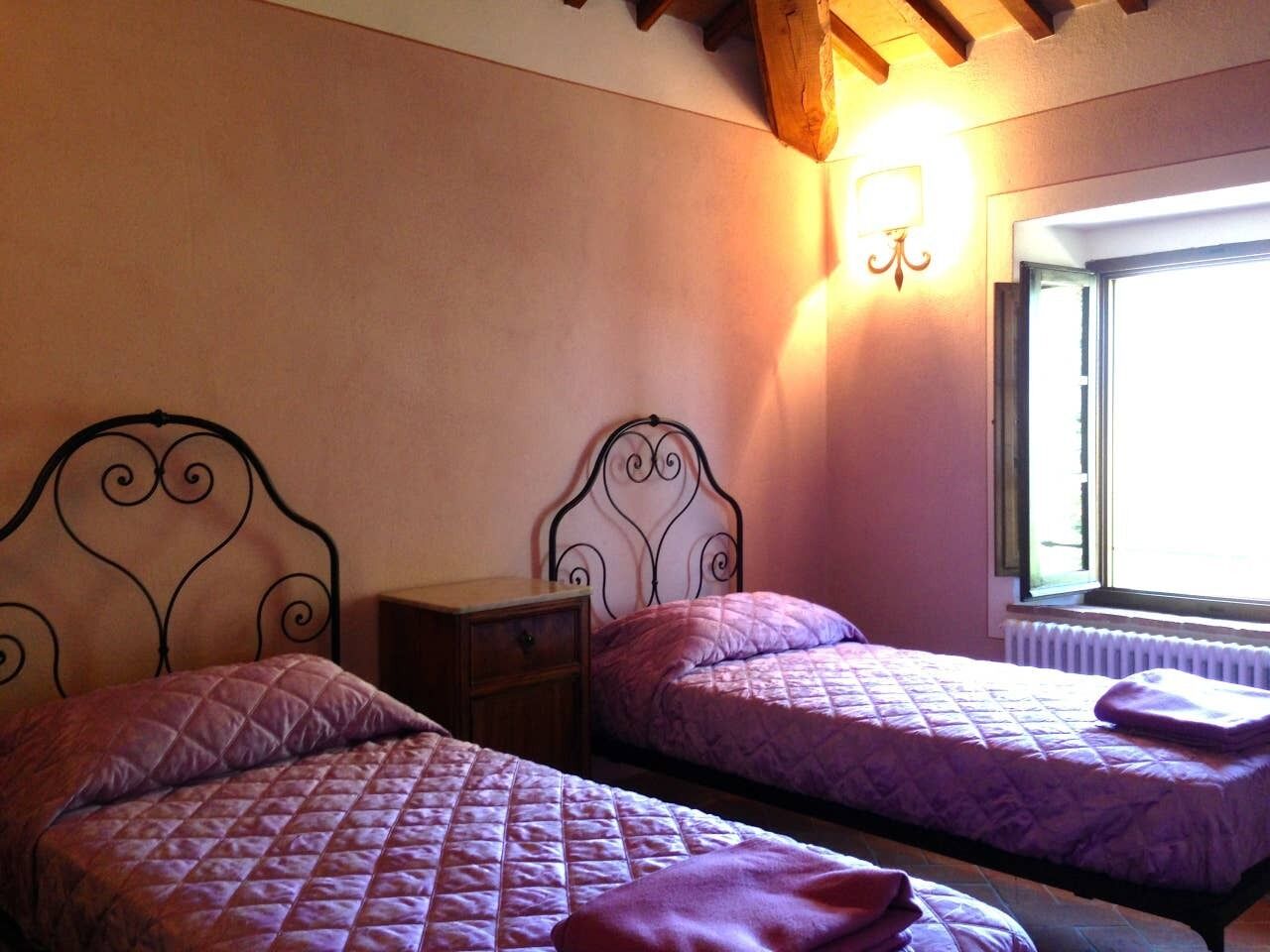 Two single beds with headboards, a nightstand, and a wall-mounted light fixture.