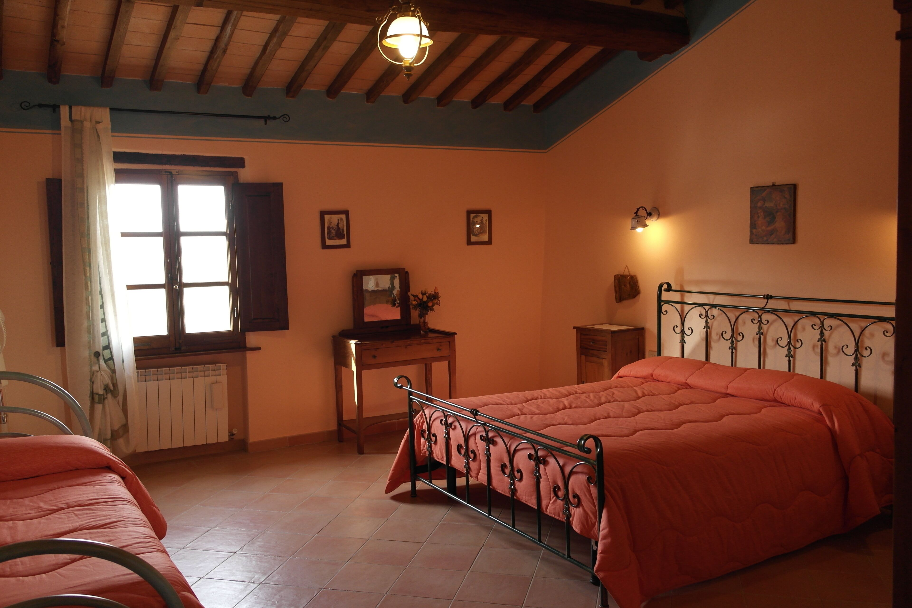 Un dormitorio con cama, escritorio, silla y ventana con cortinas.