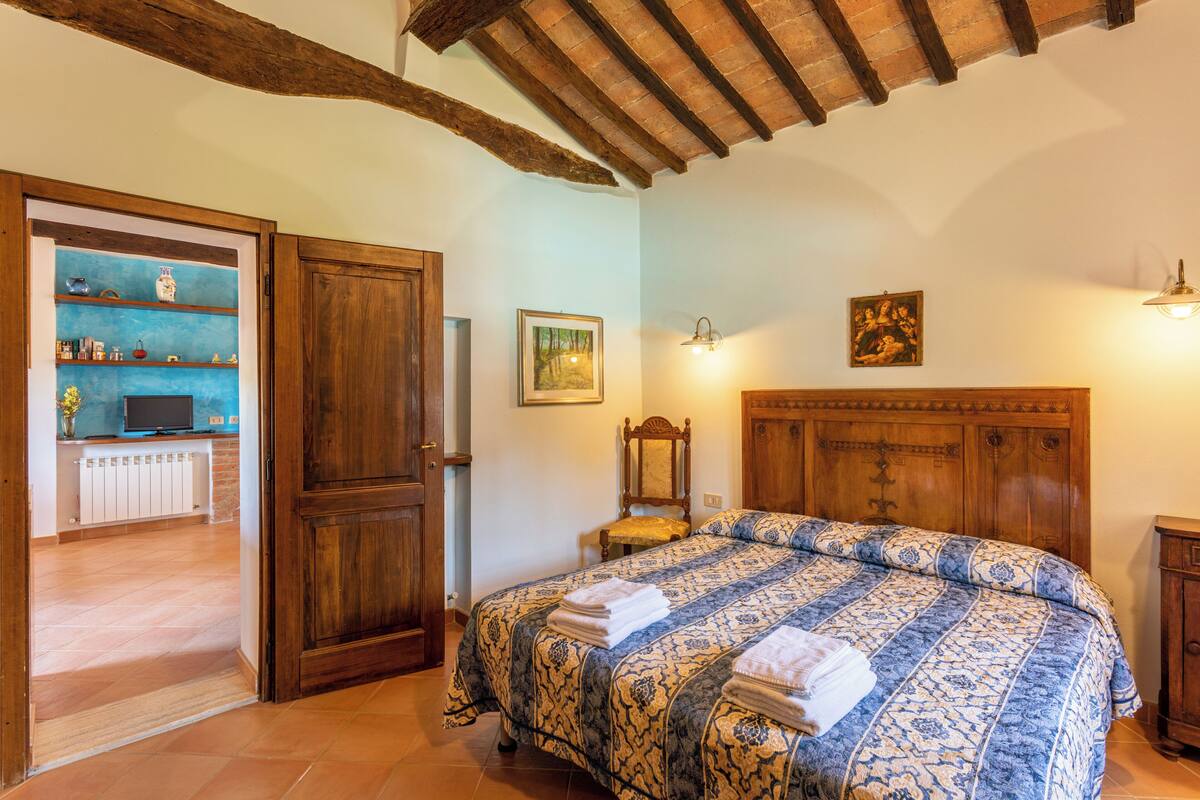 Un dormitorio con una cama grande, cabecera de madera y estante empotrado con objetos decorativos.
