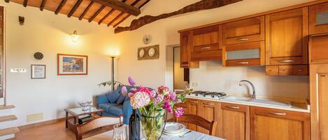 A cozy kitchen with wooden cabinets, a dining table set with plates and a vase of flowers, and a staircase leading to another level.