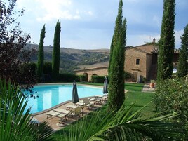 A pool area with lounge chairs and a stone building in the background.