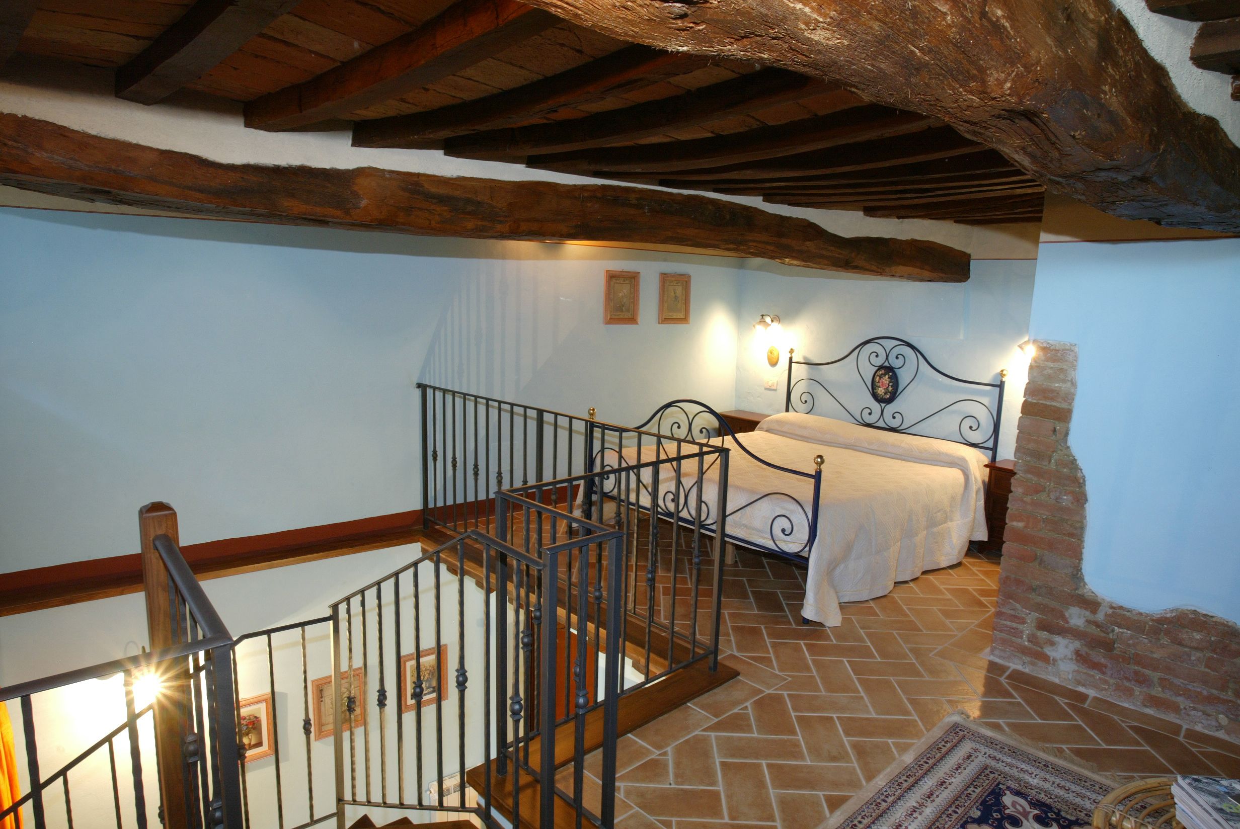 Un dormitorio con una cama, una escalera y una pared de ladrillo.