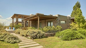 A modern house with a stone facade, a covered patio, and a stone pathway leading to the entrance. - Casa de Huespedes Gimenez Riili (Tunuyan)