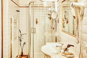 A bathroom with a glass shower enclosure, a white sink, and a mirror. - Castello di Spedaletto (Pienza)