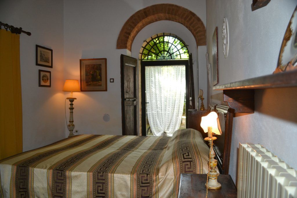 A bedroom with a bed, a lamp, a radiator, and a door leading to a balcony.