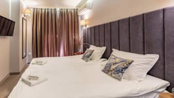 Une chambre d’hôtel avec un grand lit, un téléviseur à écran plat fixé au mur et une fenêtre avec des rideaux.