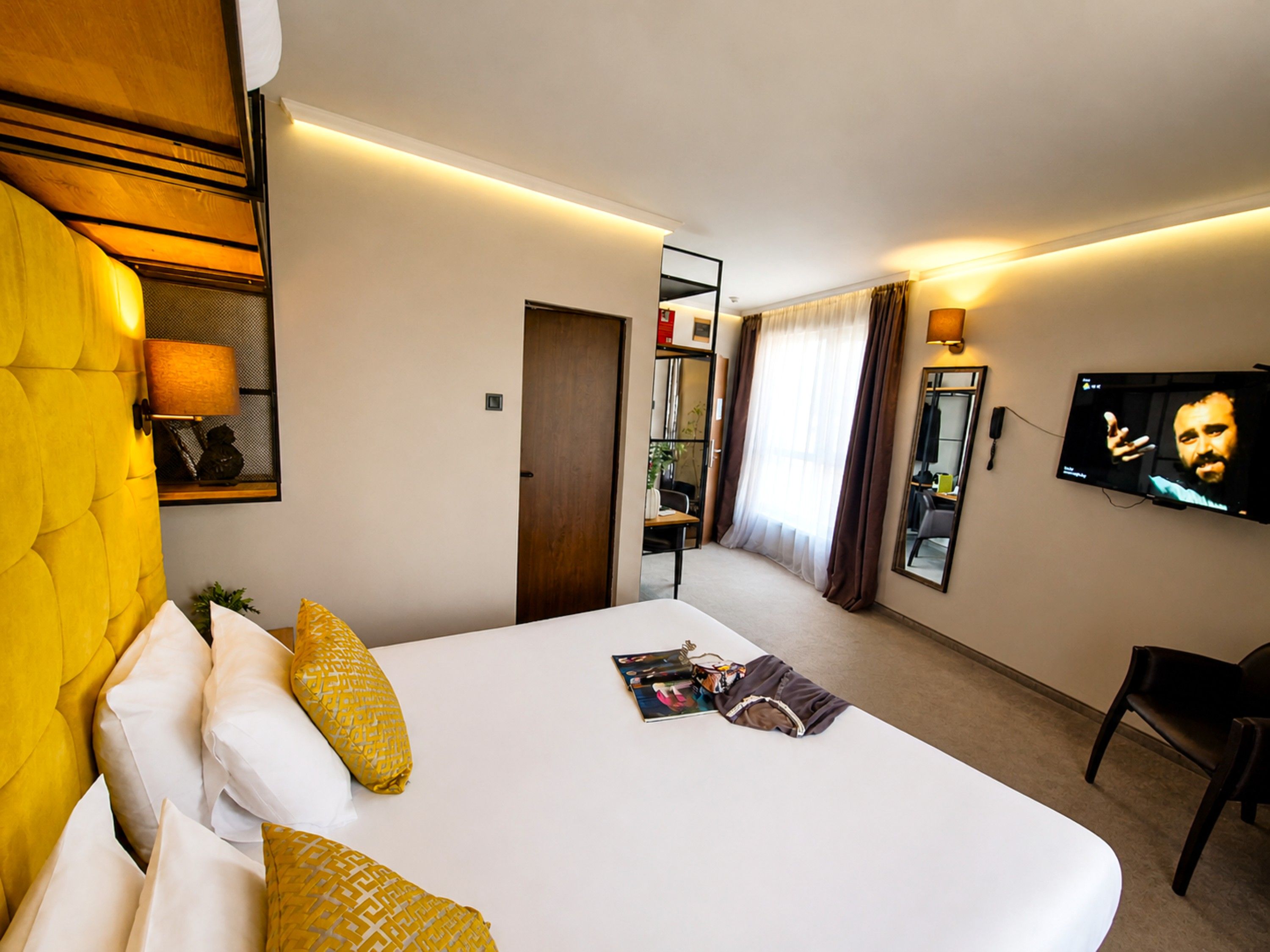 A hotel room with a bed, a television, a desk, and a chair.