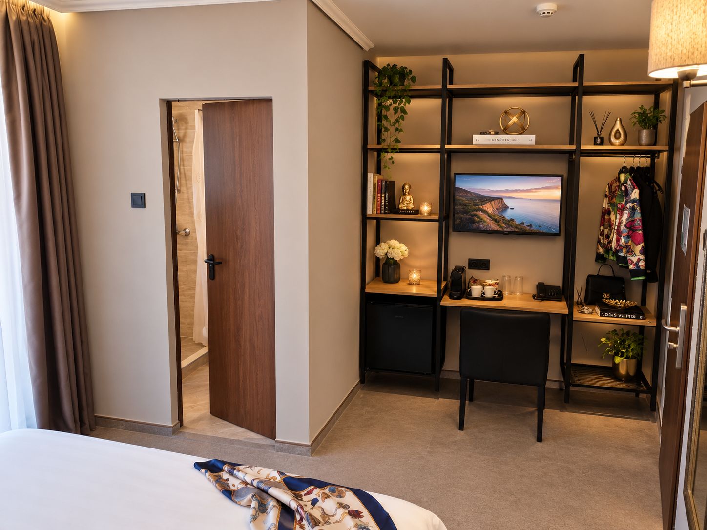 Quarto de hotel com cama, escrivaninha com computador, televisão e armário.
