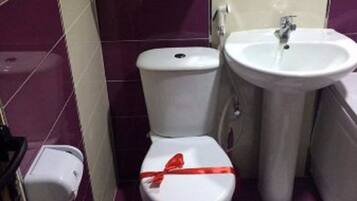 A bathroom with a toilet, sink, and a red ribbon on the toilet seat.