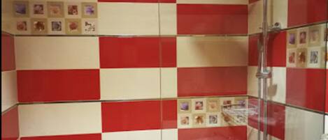 Een badkamer met rood-wit geblokte tegels, een glazen douchecabine, en een zichtbaar logo op de muur.