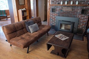 A brown leather sofa with a cushion, a wooden coffee table, and a brick fireplace with a mantel.
