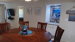 Un coin repas comprenant une table ronde en bois, six chaises et un élément décoratif central.
