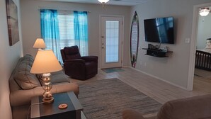 Un salon comprenant un canapé, un fauteuil inclinable, une table basse, un téléviseur et un ventilateur de plafond.