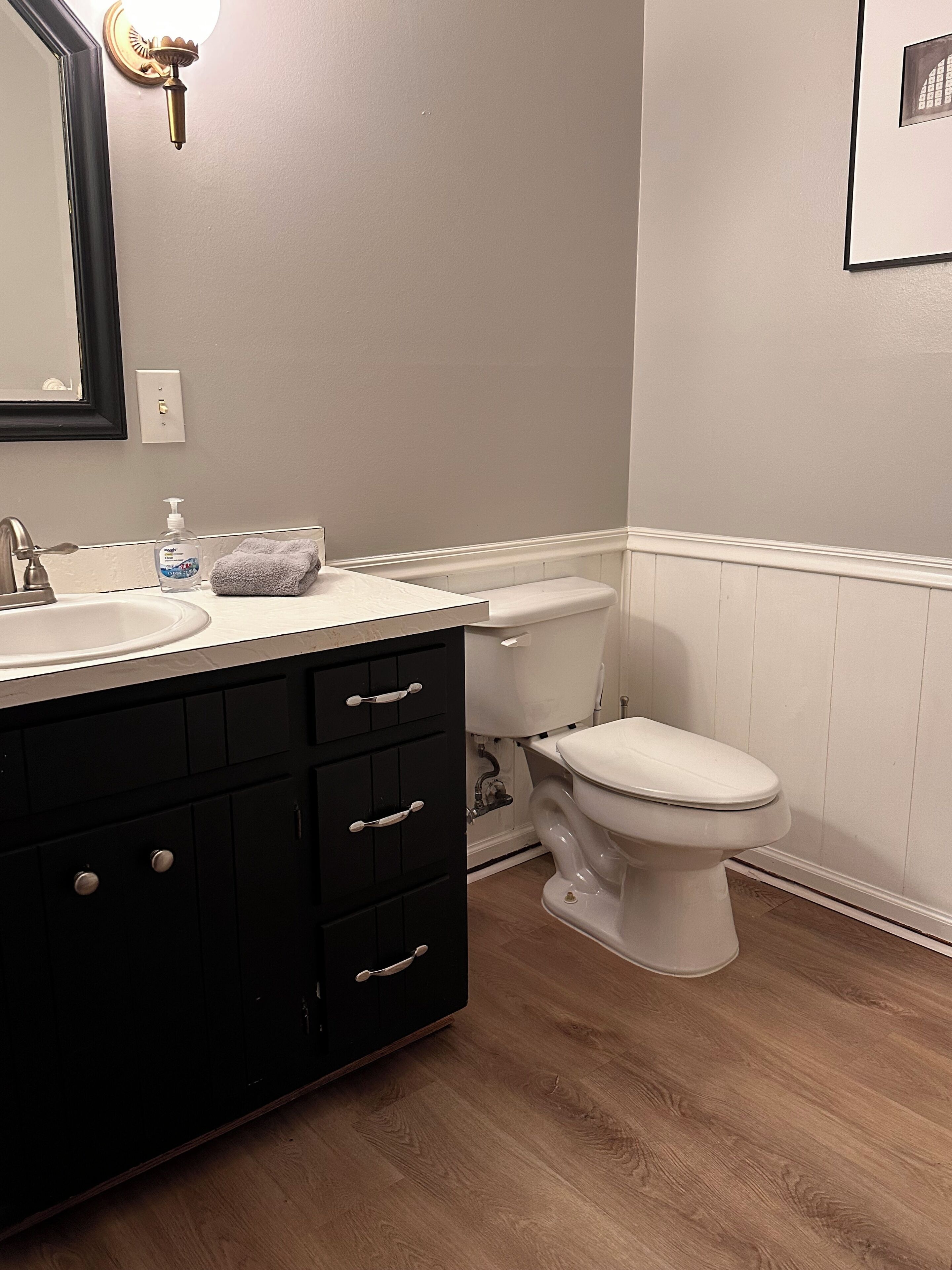 A bathroom with a white sink, black cabinet, and a toilet.