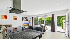 A modern kitchen with a granite countertop, a built-in stove, and a large window overlooking a garden. - 'No-Steps Noosa' - Home Away From Home 🏠  (Noosa Heads)