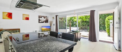 A modern kitchen with a granite countertop, a built-in stove, and a large window overlooking a garden.
