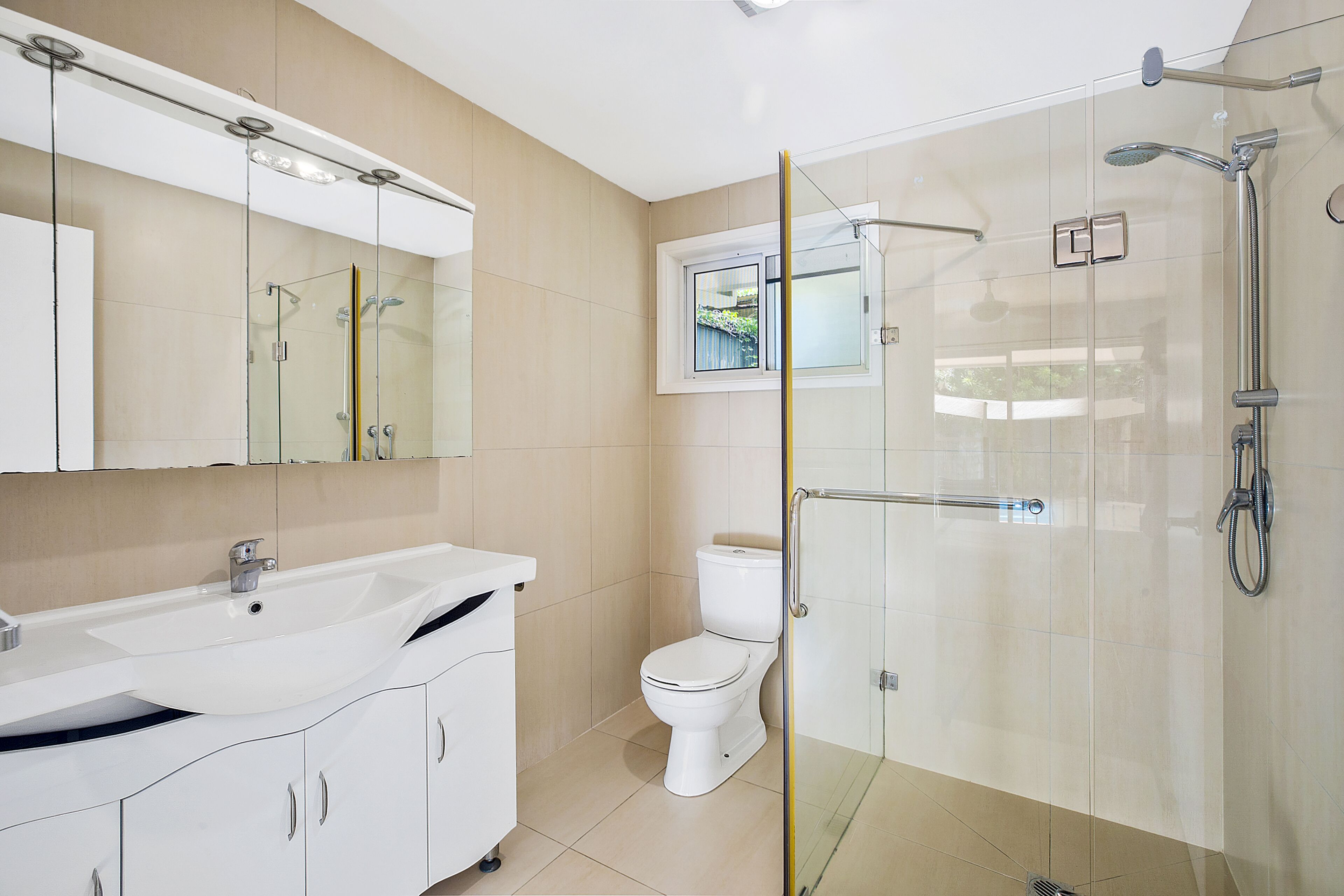 Un baño moderno con ducha acristalada, lavamanos blanco y retrete.