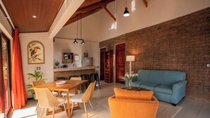 Un amplio espacio de estar con mesa y sillas de comedor, un sofá y una cocina al fondo.