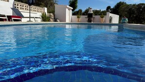Una piscina con agua azul cristalina, rodeada de edificios blancos y follaje.