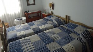 Une chambre avec deux lits, un bureau, une chaise, une lampe et un miroir.