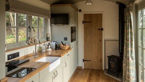 Eine Küche mit Holzausstattung, einem großen Fenster, einem eingebauten Herd und einer Spüle.