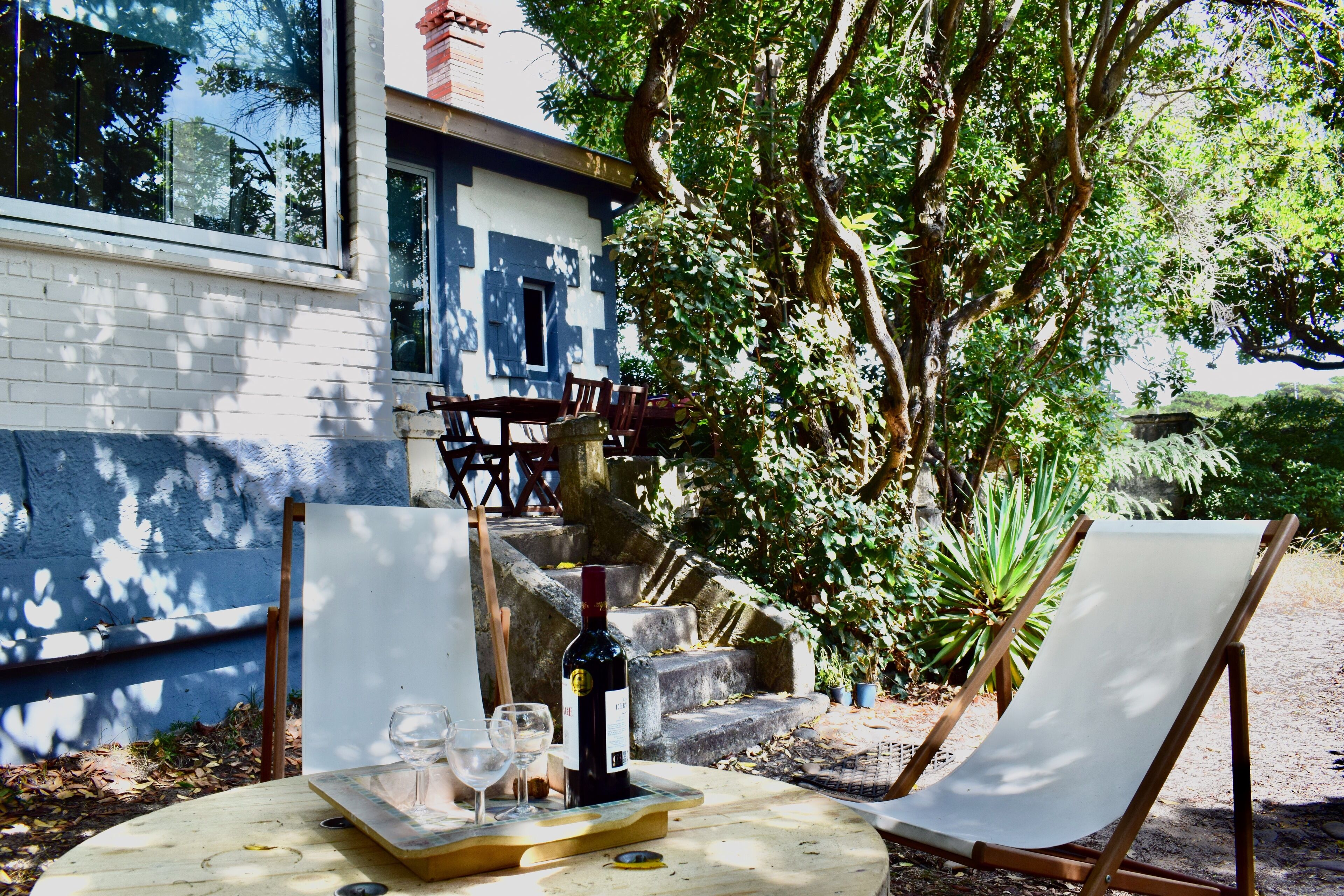 An outdoor seating area with a table set for two, a wine bottle, and two glasses.
