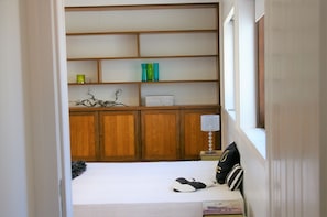 Une chambre à coucher avec un lit, une armoire en bois, une table de chevet et une fenêtre.