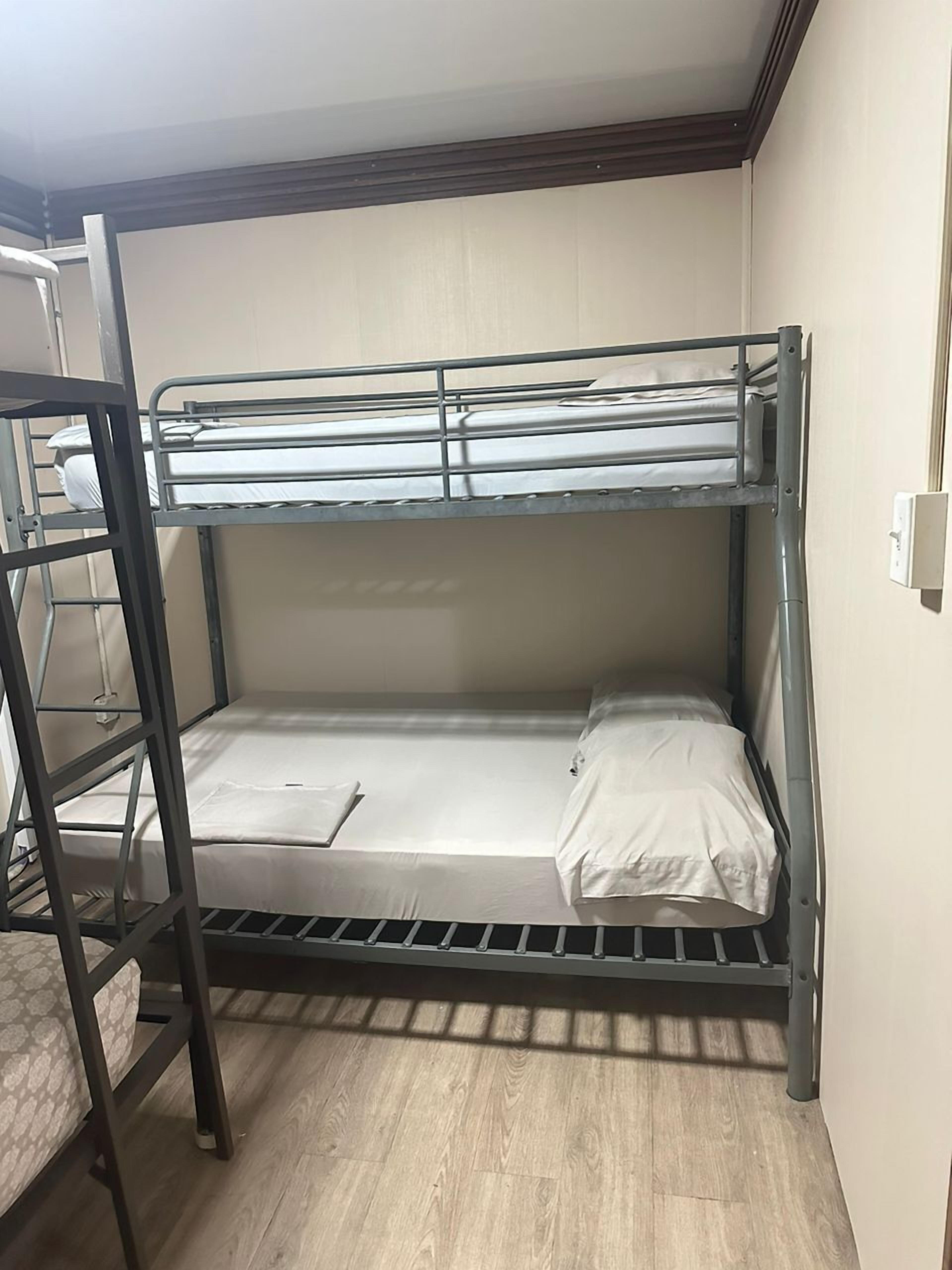 A bunk bed room with a wooden floor and a white wall.