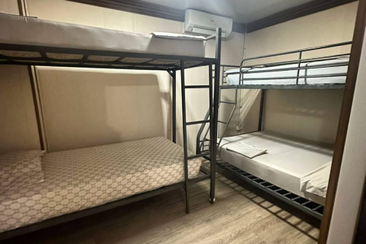A bunk room with two bunk beds, a ladder, and an air conditioning unit.